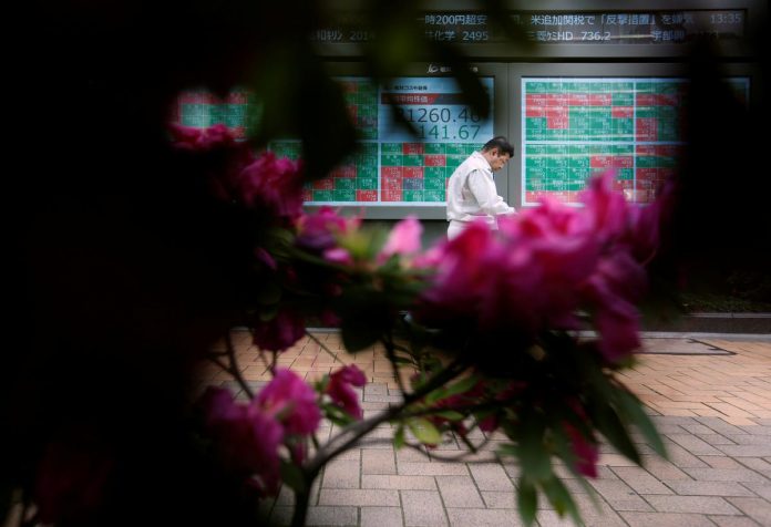 A passerby walks past in front of a stock quotation board outside a brokerage in Tokyo