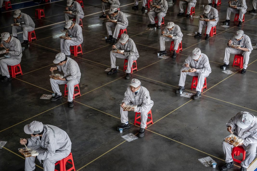 This photo taken on March 23, 2020 shows employees eating during lunch break at an auto plant of Dongfeng Honda in Wuhan in China’s central Hubei province.