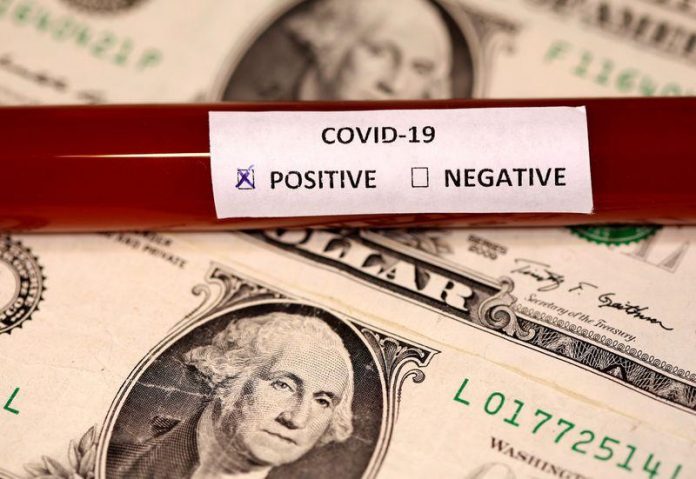 A test tube labelled with the coronavirus is placed on U.S. dollar banknotes