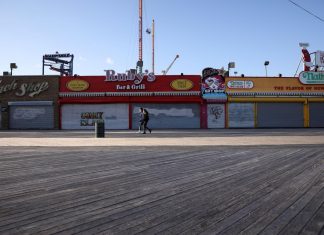 People wearing protective masks walk past closed shops on the the Coney Island boardwalk during the outbreak of coronavirus disease (COVID-19) in Brooklyn, New York, U.S.