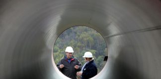 Engineers talk as they stand next to pipes to be used for a pipeline that is part of the Sakhalin-2 project, some 220 km (137 miles) north of Yuzhno-Sakhalinsk on Sakhalin Island October