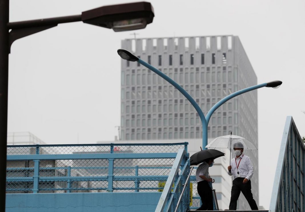 A man wearing a protective face mask, following the coronavirus disease (COVID-19) outbreak, walks on a pedestrian overpass at a business district in Tokyo, Japan
