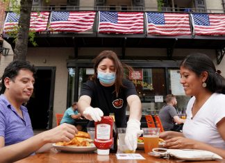 As Phase One of reopening begins in Northern Virginia, a waitress with a face mask to protect against the coronavirus disease (COVID-19) serves diners at a restaurant in Alexandria, Virginia, U.S.