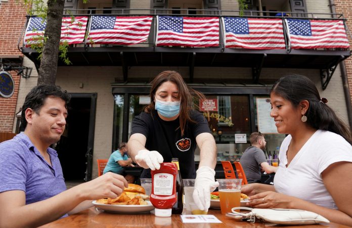 As Phase One of reopening begins in Northern Virginia, a waitress with a face mask to protect against the coronavirus disease (COVID-19) serves diners at a restaurant in Alexandria, Virginia, U.S.