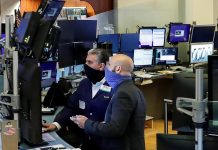 Traders wearing masks work, on the first day of in person trading since the closure during the outbreak of the coronavirus disease (COVID-19) on the floor at the New York Stock Exchange (NYSE) in New York, U.S.