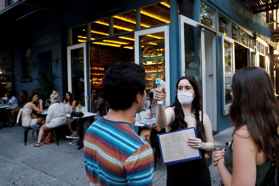 A waitress takes the temperature of customers as they arrive to eat at Dudley's as restaurants are permitted to offer al fresco dining as part of phase 2 reopening during the coronavirus disease (COVID-19) outbreak in the Lower East Side neighborhood of Manhattan in New York City, U.S.