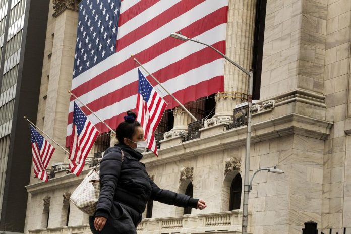 A pedestrian with a mask walks past of the New York Stock Exchange (NYSE) in New York, U.S., March